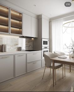 a modern kitchen with white cabinets and marble counter tops, along with a dining room table