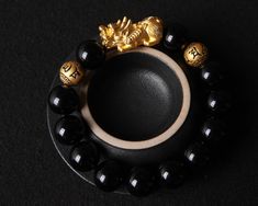 This Wealth and Luck Black Obsidian Pixiu Bracelet is a handmade item that features a 24k gold Piyao and two mantra beads, a mythical creature known for its ability to attract wealth and good luck. The bracelet is also crafted with genuine obsidian stones, a powerful gemstone believed to offer protection and grounding. Deatails: - Bracelet Design: 1 Piyao Charms + 2 Mantra Gold beads + 12 Black Obsidian Beads - Size:  (all size could be customized as you wish) Pixiu: 27.5*12.3*12.2 MM;  Mantra B Traditional Black Bracelet As Gift, Traditional Black Bracelet Gift, Traditional Black Bracelet For Gift, Traditional Black Beaded Bracelets As Gift, Obsidian Beaded Bracelets As Gift, Spiritual Black Beaded Wristband As Gift, Black Beaded Crystal Bracelet Gift, Black Crystal Bracelet With Gemstone Beads As Gift, Black Spiritual Beaded Bracelets As Gift