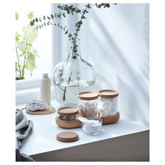 some glass jars with flowers in them on a table next to a window sill