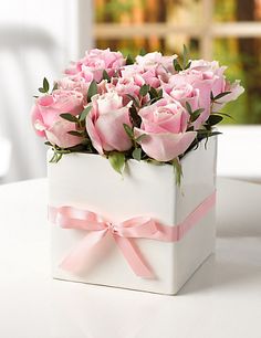 a white box filled with pink roses on top of a table