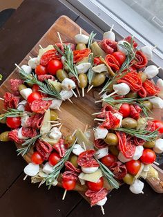 a wreath made out of vegetables and meats on a cutting board next to a window