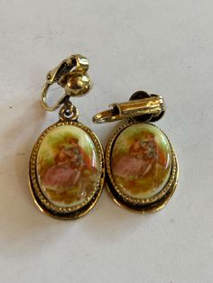 Vintage Goldtoned Clipon Earrings with old Courting Scene measuring 1x3/4" Vintage Dangle Earrings For Anniversary, Vintage Hallmarked Dangle Earrings, Vintage Metal Earrings For Anniversary, Collectible Victorian Oval Earrings, Vintage Oval Hallmarked Earrings, Vintage Oval Earrings Hallmarked, Victorian Oval Earrings For Collectors, Vintage Oval Pierced Earrings, Antique Clip-on Earrings For Anniversary