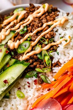 a bowl filled with rice, meat and veggies next to sliced carrots