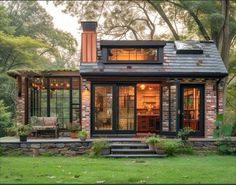 a small brick house with lots of windows on the front and side walls, surrounded by trees