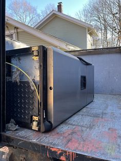 a large metal box sitting on the back of a flatbed truck in front of a house