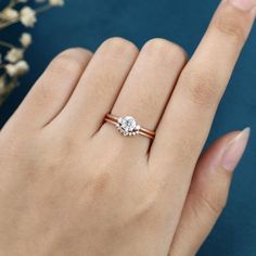 a woman's hand with a diamond ring on her finger and flowers in the background