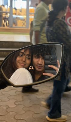 two people taking a selfie in the side mirror of a car