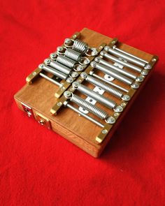 a wooden box with many bolts in it on a red cloth covered tablecloth,