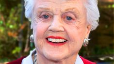 an older woman with white hair and earrings smiling at the camera while standing in front of a car