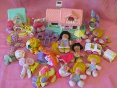 there are many small toys on the pink tablecloth, including teddy bears and dolls