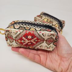 two small purses are being held by a person's hand on a white surface