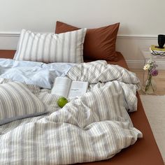 an unmade bed with striped sheets and pillows