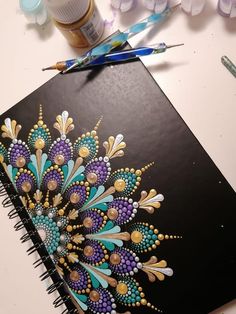 an artistically painted notebook with some paintbrushes next to it