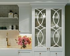 a kitchen with white cabinets and pink flowers