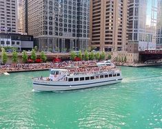 a boat full of people is in the water near some tall buildings and skyscrapers