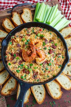 a skillet filled with shrimp and bread on top of a cutting board next to sliced celery