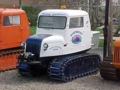 there is a small white truck and an orange tractor in the parking lot next to each other