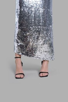 This mid-rise Silver Sequin Diagonal Maxi Skirt has an asymmetrical cut at the bottom. This skirt is noted for its uniqueness in design and its versatility. This product is styled with the Black Satin Arc-Cut Top.