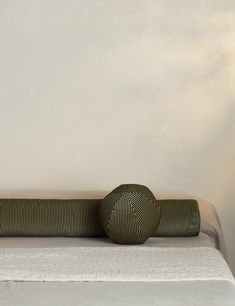 a bed with two round pillows on top of it next to a wall mounted lamp