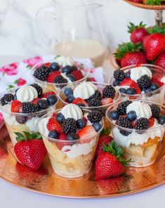 small desserts are arranged on a tray with strawberries and blackberries in them