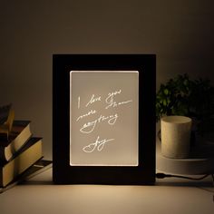 a light box with writing on it sitting next to some books and a potted plant