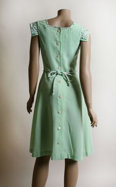 "FREE DOMESTIC SHIPPING! <3 ♥ Lovely vintage 1970s mint green cotton dress, with floral accents! ♥ Buttons up the back! Fitted waist, with matching floral waist tie rope. ♥ Cap style sleeves, with floral flap accent. Matching trim on the front skirt pockets! ♥ Cotton, crepe textured. Semi-sheer, you'll probably want a slip under. ♥ In great condition! * measurements when flat * Bust - 19\" across Shoulders - 14\" across Waist - 13\" across Hips - 21\" across Bodice length - 16\" Length - 40\" Green Retro Vintage Dress, Green Vintage Style Dress For Summer, Green Vintage Dress For Summer, Green Knee-length Vintage Dress, 1950s Green Short-sleeved Dress, Green Buttoned Dress For Daywear, Green Summer Dress For Vintage Fashion, Green Summer Dresses For Vintage Fashion, Green Buttoned Dress For Garden Party