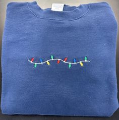 Christmas Lights Embroidered Sweatshirt!  Look so cute in this Unisex sweatshirt featuring a minimalist string of Christmas lights. Perfect for your Christmas party, Wear it to work, Ugly Christmas Sweater or as PJ's. Navy Sweatshirt shown in pic.  you select what color sweatshirt! Have yourself a MERRY lil Christmas!! Casual Embroidered Sweatshirt For Holiday, Casual Holiday Embroidered Sweatshirt, Christmas Embroidered Crew Neck Sweatshirt, Christmas Crew Neck Sweatshirt With Embroidered Graphics, Christmas Holiday Embroidered Sweatshirt, Mommy Friends, Nurse Love, Minimalist Christmas, Embroidered Sweatshirts