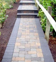 a brick walkway with steps leading up to flowers and trees in the background, surrounded by greenery