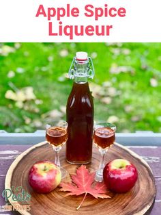 an apple spice liqueur is served on a wooden platter with two glasses