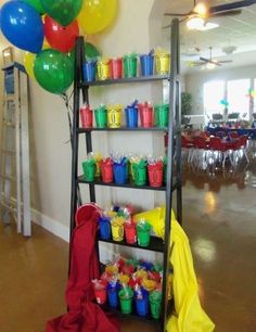 a room filled with lots of balloons and plastic cups on a shelf next to a red umbrella