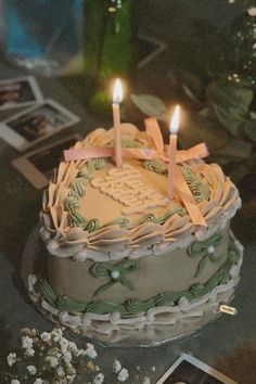 a birthday cake with two candles on it and pictures in the backgroung