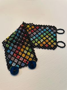 two pieces of beaded jewelry sitting on top of a white table next to each other