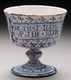 a blue and white bowl with writing on the inside is sitting on a pedestal in front of a black background