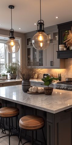 a kitchen island with stools and lights hanging from it's ceiling above it