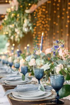 the table is set with blue dishes and place settings