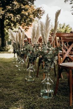 the chairs are lined up with flowers and greenery in vases on each side