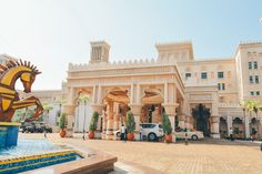 a large building with a fountain in front of it and cars parked on the street