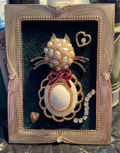 an elaborately decorated brooch with pearls and bows in a gold frame on a table