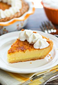 a slice of pie with whipped cream on top sits on a white plate next to a fork