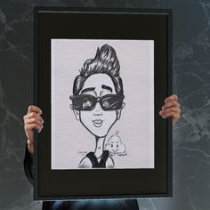 a person holding up a drawing of a woman wearing sunglasses