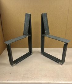 two metal chairs sitting next to each other on top of a white table with a cardboard box in the background