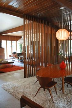 a dining room table and chairs in front of a wooden wall with vertical slats