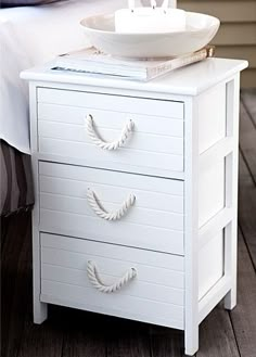 a white nightstand with two drawers and a bowl on top