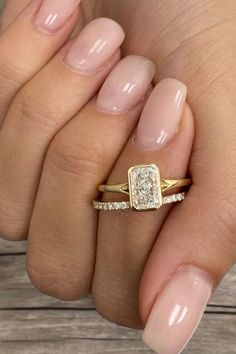 a woman's hand holding a gold ring with two diamonds on the middle and one diamond