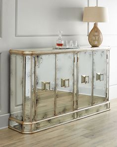 a mirrored cabinet with two doors and a lamp on the side table in front of it