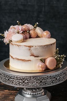 a white cake with pink flowers and seashells is on a silver platter