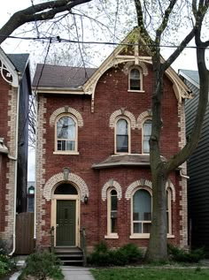 a red brick house with arched windows and a green door