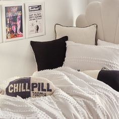 a bed with white sheets and pillows in a bedroom next to pictures on the wall