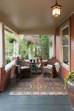 a porch with two wicker chairs and a rug on the floor