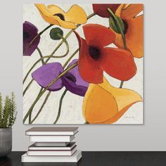 an abstract floral painting on a wall above a stack of books and a potted plant